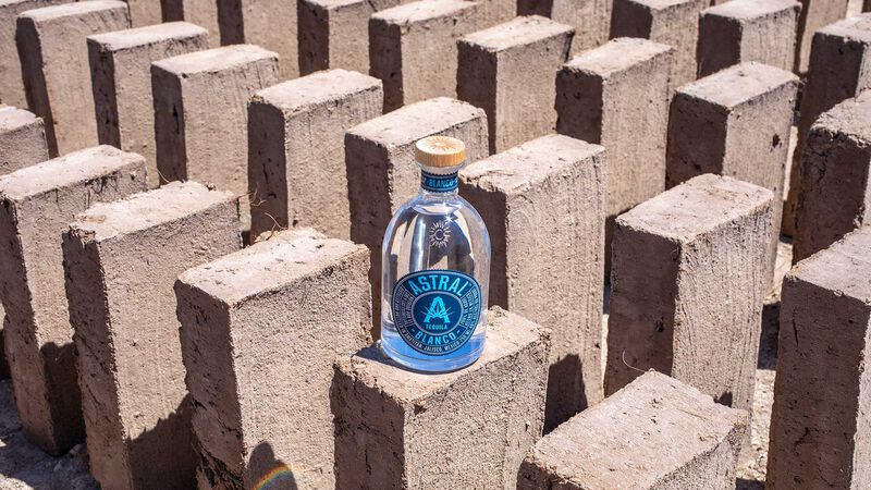 A bottle of Astral Tequila is showcased on recycled agave bricks